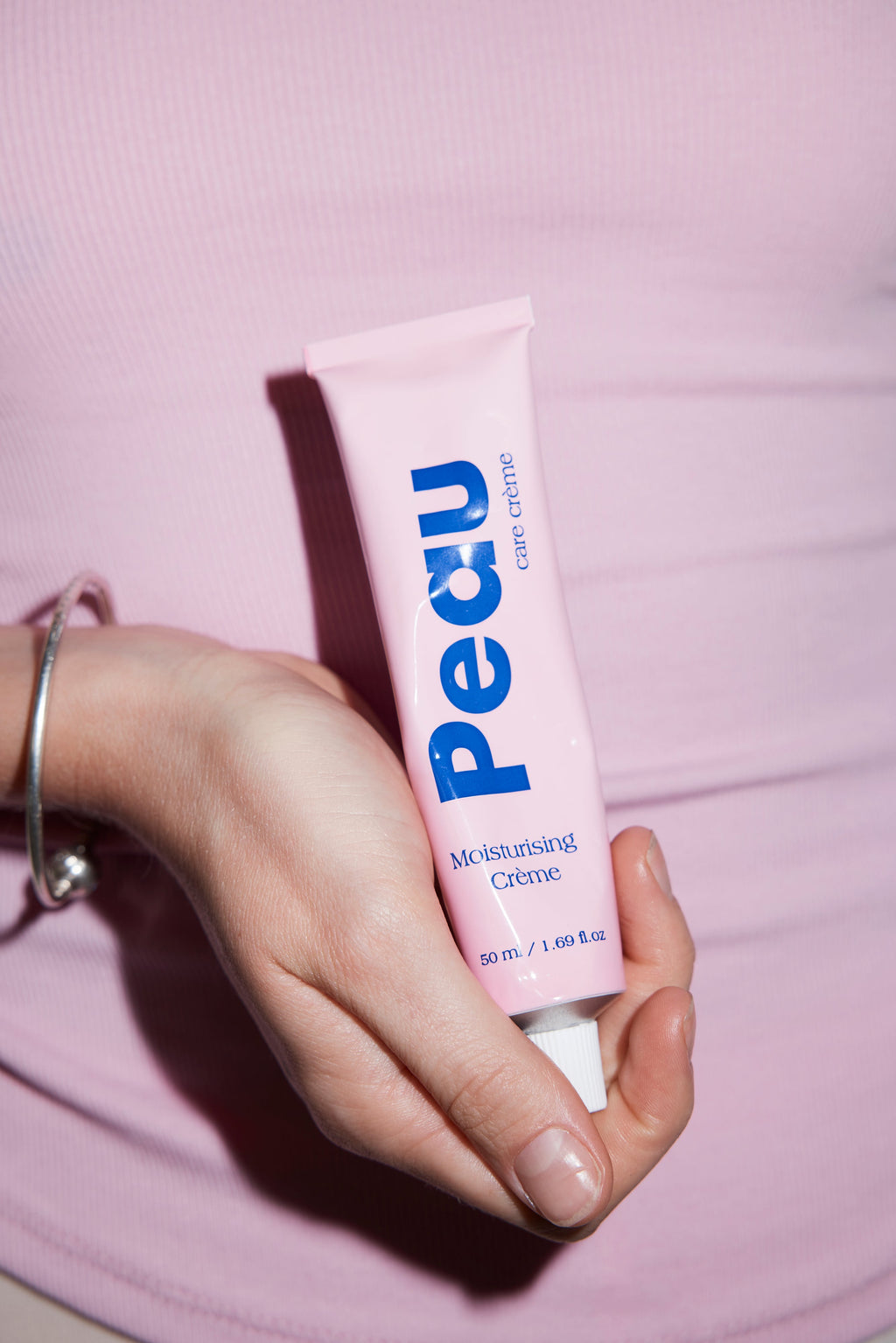 Close-up of Peau Moisturising Crème being applied, showing the lightweight texture of the barrier-repair formula.